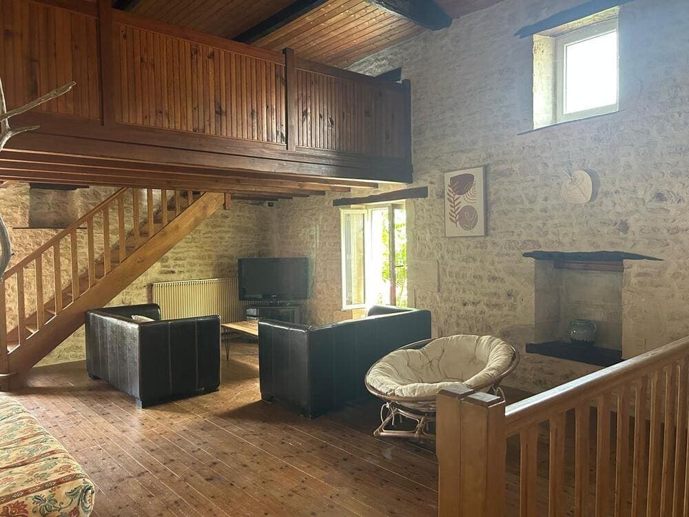 Le premier étage du Gîte Pampas au Domaine du Vieux Lavoir, révélant un deuxième coin salon confortable avec télévision . Au fond, l'escalier menant à la mezzanine ajoute un espace supplémentaire. Ces zones de détente sont idéales pour les familles ou groupes d'invités séjournant pour vos mariages et grandes réceptions dans les Deux-Sèvres, offrant intimité et divertissement.
