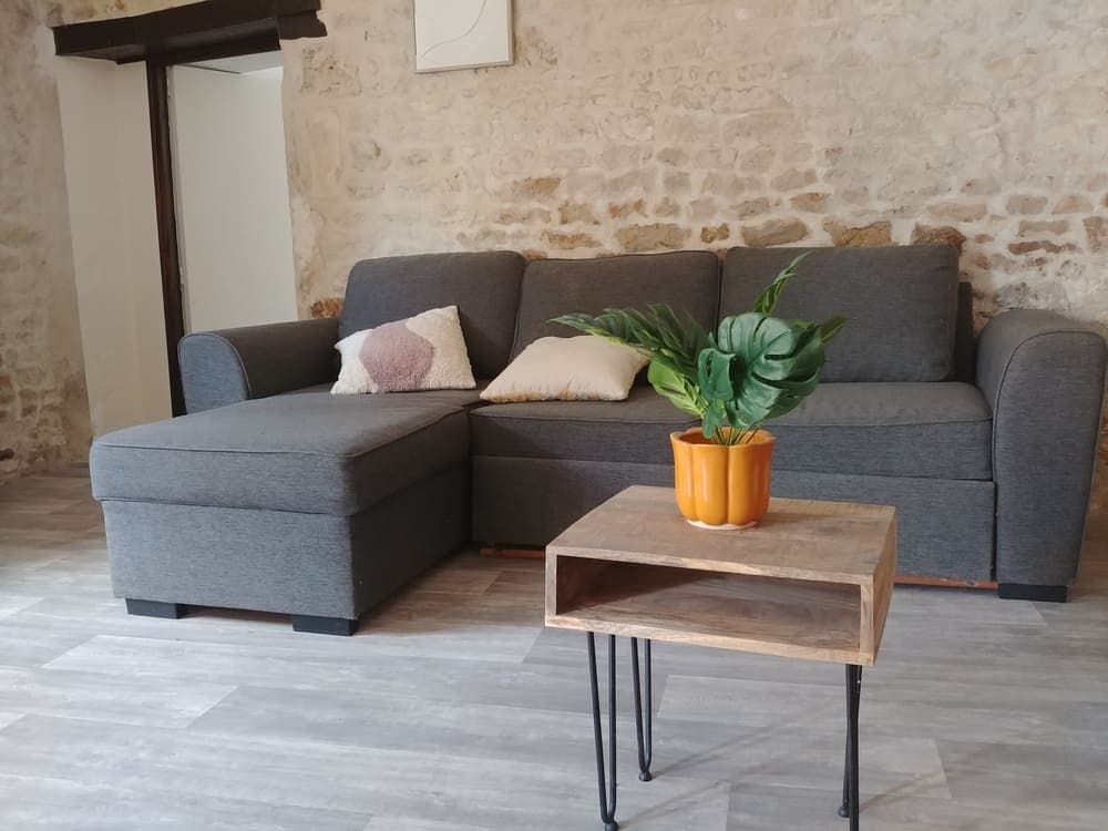 Gros plan sur le confortable canapé d'angle et la table basse du Gîte Rose au Domaine du Vieux Lavoir. Cet espace de salon est idéal pour la détente et les moments conviviaux, offrant un confort optimal à tous les invités. Faisant partie de notre gîte entièrement accessible aux Personnes à Mobilité Réduite (PMR), il est parfait pour se reposer après les célébrations de vos mariages et grandes réceptions dans les Deux-Sèvres.