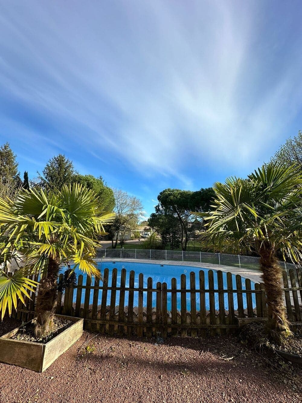 La piscine du Domaine du Vieux Lavoir, encadrée au premier plan par de charmants petits palmiers, créant une atmosphère exotique et propice à la détente. Cet espace invite au farniente et au rafraîchissement, offrant un cadre dépaysant pour les invités de vos mariages et grandes réceptions dans les Deux-Sèvres. Un véritable havre de paix pour profiter du soleil.