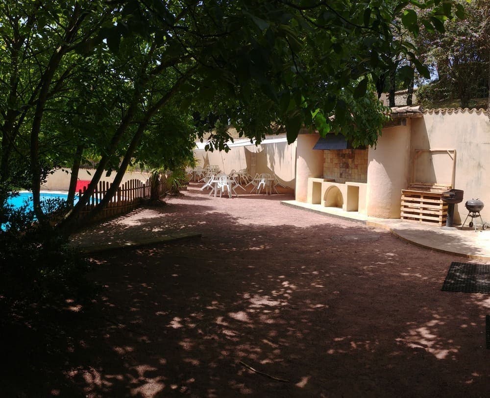Vue depuis la pool house du Domaine du Vieux Lavoir, montrant sa terrasse ombragée au premier plan. En second plan, on découvre la grande terrasse ombragée par des voiles, aménagée avec tables et chaises, offrant un espace idéal pour les repas en extérieur ou les cocktails. Une partie de la piscine est également visible, dépendant harmonieusement de ces zones de détente. Ces aménagements sont parfaits pour les invités de vos mariages et grandes réceptions dans les Deux-Sèvres, garantissant confort et convivialité en plein air.