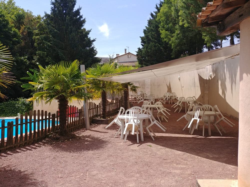La spacieuse terrasse ombragée du Domaine du Vieux Lavoir, protégée par d'élégantes voiles d'ombrage , offrant un lieu de détente idéal avec une vue partielle sur la piscine en contrebas sur la gauche. Cet espace extérieur privilégié est parfait pour les cocktails, les pauses et les moments conviviaux lors de vos mariages et grandes réceptions dans les Deux-Sèvres, garantissant confort et fraîcheur à vos invités.