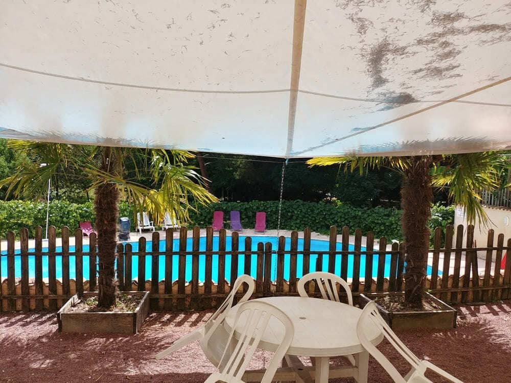 La piscine du Domaine du Vieux Lavoir, visible depuis la terrasse ombragée par des voiles élégantes, offrant une vue agréable et une surveillance aisée. Cet espace confortable est parfait pour se détendre tout en gardant un œil sur les baignades, ou simplement pour profiter du cadre lors de vos mariages et grandes réceptions dans les Deux-Sèvres. Un point de vue privilégié pour apprécier l'espace aquatique en toute sérénité.