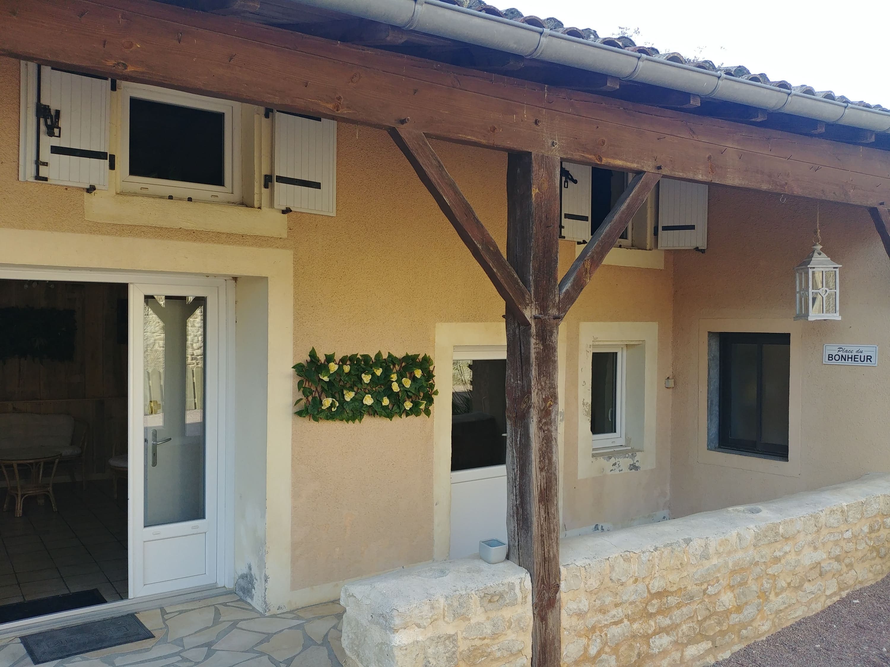 La charmante façade du Gîte Lilas au Domaine du Vieux Lavoir, invitant à la découverte de nos hébergements. On y aperçoit sa porte d'entrée accueillante, ses fenêtres lumineuses, une authentique poutre en bois qui lui confère son cachet, un cadre débordant de fleurs colorées et une petite lanterne à l'ancienne . Ces détails soignés soulignent l'attention que nous portons à l'esthétique de nos gîtes, offrant un cadre pittoresque et chaleureux pour vos mariages et grandes réceptions dans les Deux-Sèvres.