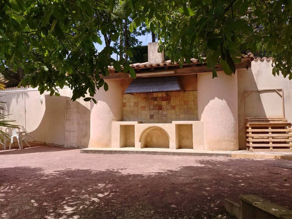 Vue pittoresque sur l'ancienne cuisine d'été du Domaine du Vieux Lavoir, prise depuis la terrasse de la pool house. Cet élément architectural plein de caractère témoigne de l'histoire du lieu, ajoutant une touche d'authenticité et de charme rustique. Il fait partie intégrante du cadre unique que nous offrons pour vos mariages et grandes réceptions dans les Deux-Sèvres, invitant à la découverte des moindres recoins de notre domaine.